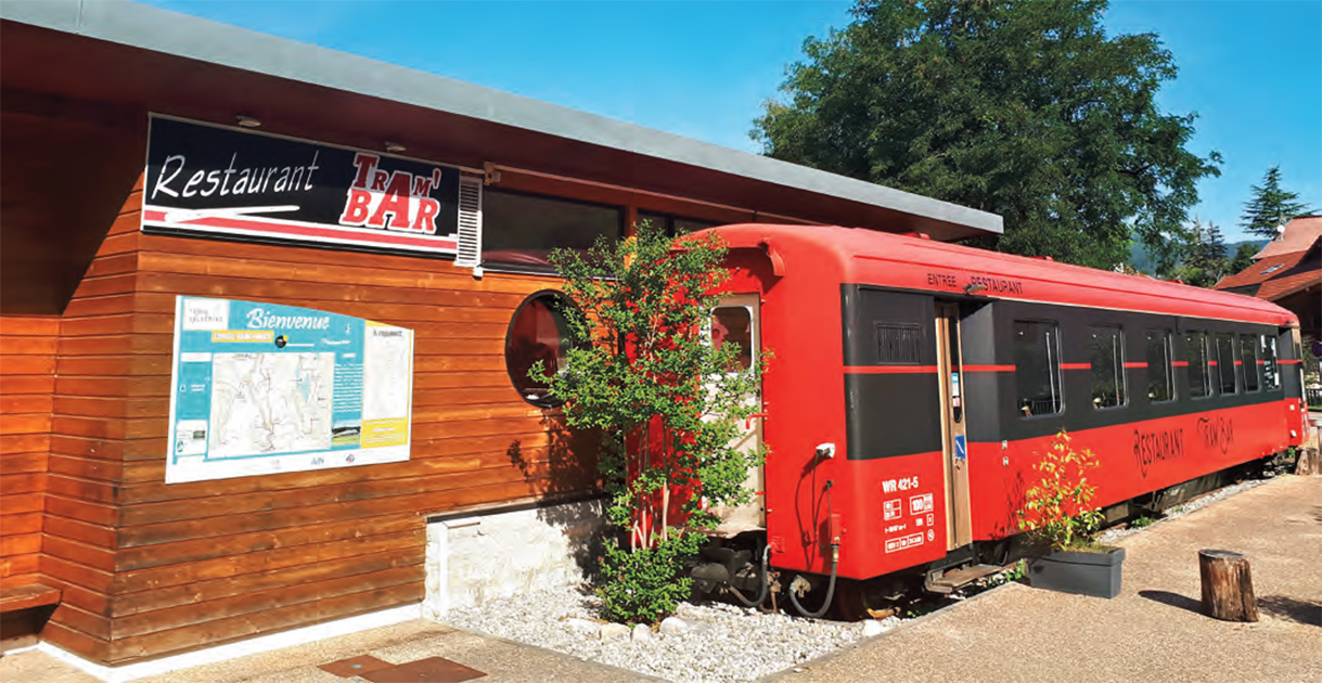 Depuis 2022, le restaurant le Tram’Bar est installé au coeur du village de Confort dans l’Ain. Il est aménagé dans une voiture voyageurs et doté d’une terrasse. Une étape de choix pour les touristes, les randonneurs et les cyclistes qui empruntent la voie douce aménagée sur l’ancienne voie ferrée.