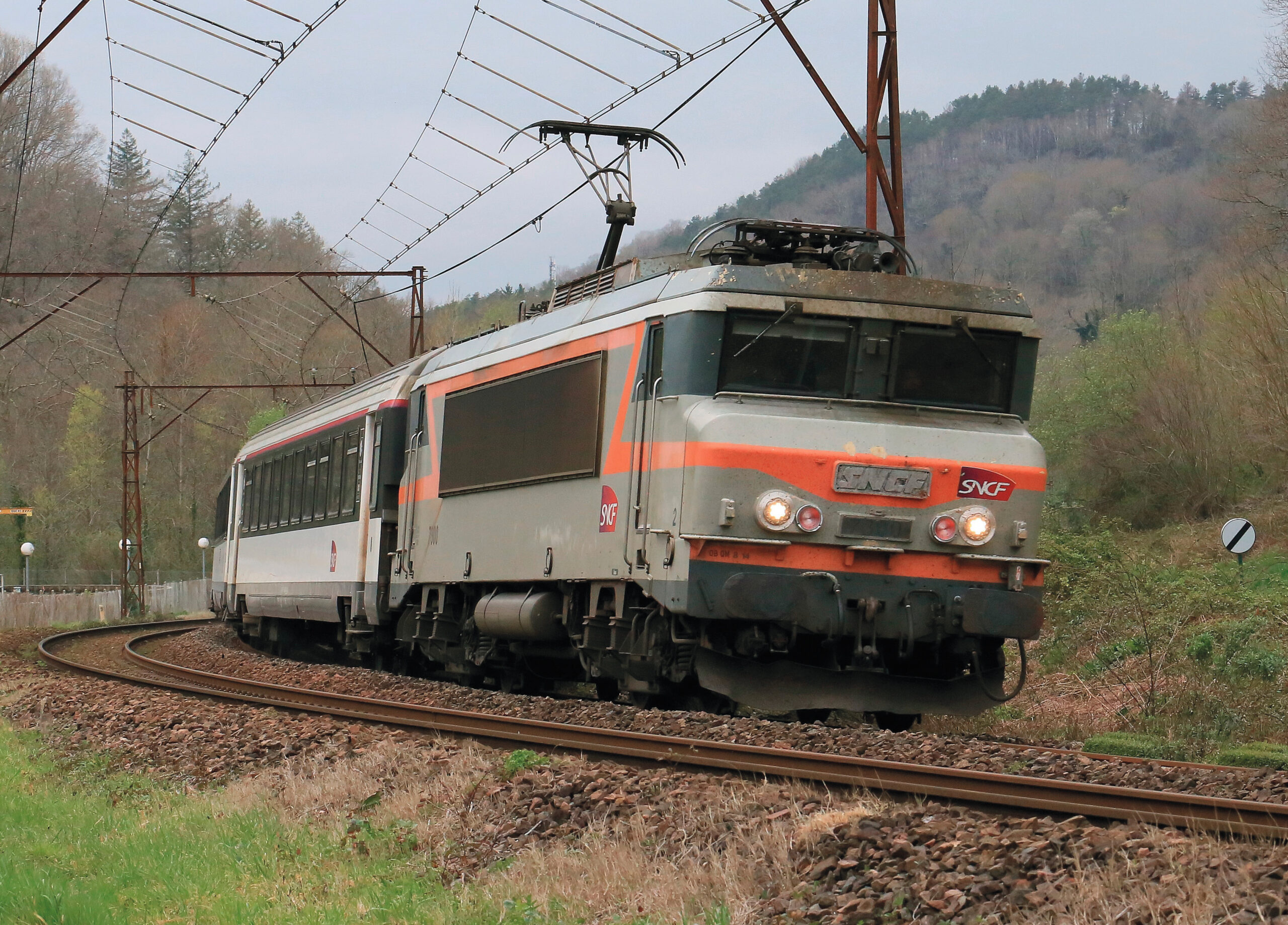 Comme déjà beaucoup de ses consoeurs, la BB 7300 a reçu de nouveaux phares à LED. Elle est vue arrivant à Lourdes en tête de l’Intercités de nuit 3731 Paris-Austerlitz - Tarbes, sous caténaire Midi typique de la région (2 avril 2025).