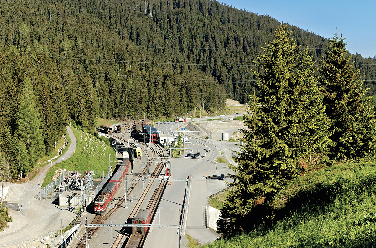 Depuis le portail du tunnel de la Vereina, vue sur le terminal de Klosters-Selfranga. Le train de voyageurs visible vient de quitter le tunnel de Zugwald et va disparaître dans celui de la Vereina (Bernhard Studer ; 11 juin 2006).