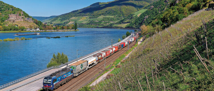 Une Vectron bleu SBB Cargo International sur un train pour l’Italie passe Assmannshausen, sur la rive droite du Rhin (23 avril 2024 ; F. Pobez).