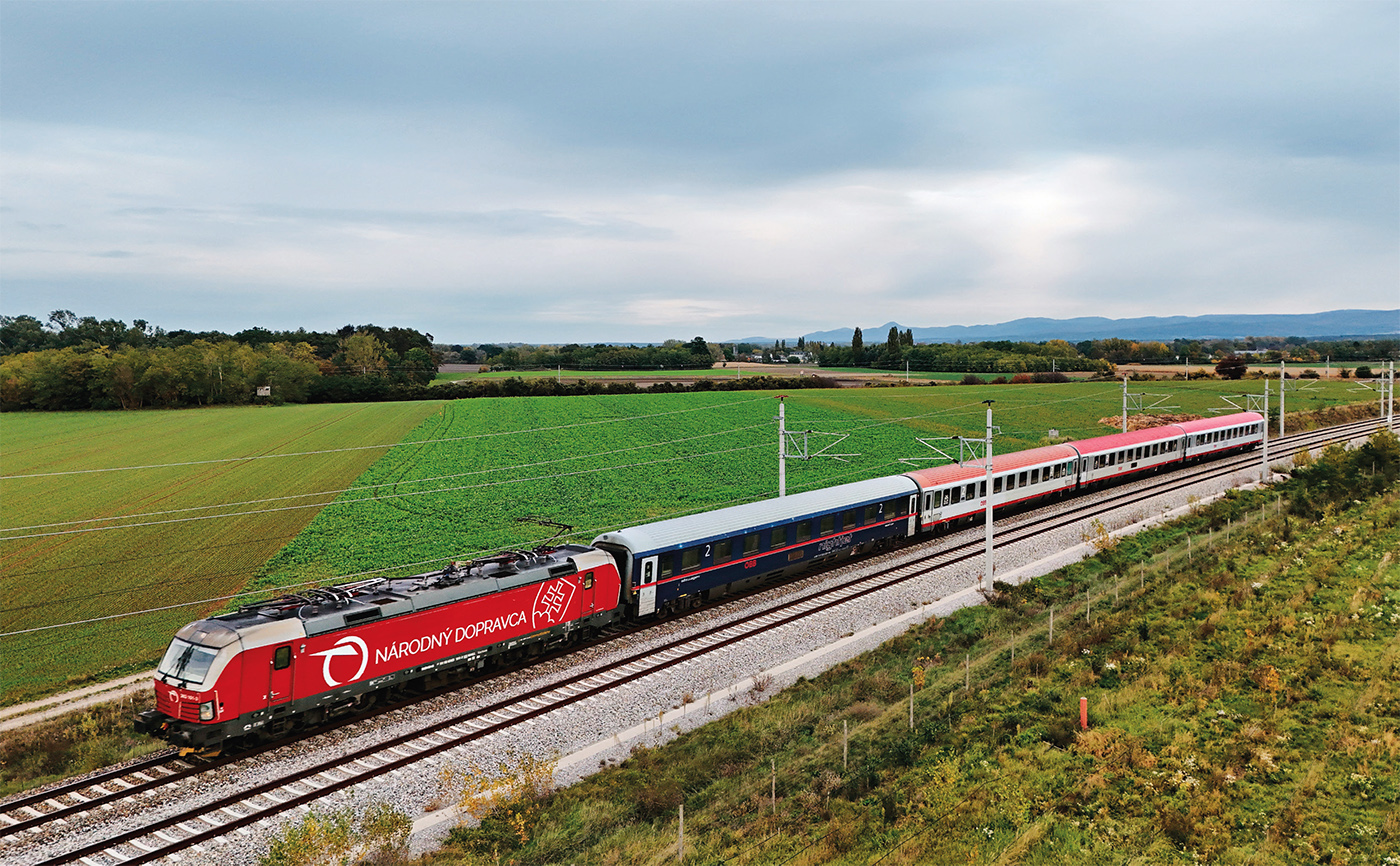 Le train REX 8 2523, assuré par une rame de quatre voitures ÖBB, dont une voiture Nightjet places assises, remorquée par la Vectron MS 383 001-3 louée par les ZSSK à Rolling Stock Lease, vient de quitter Marchegg où a eu l’échange de personnel ZSSK/ÖBB (14 octobre 2025).