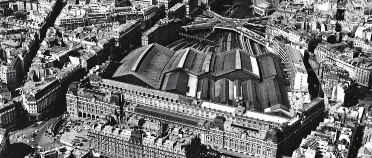 Paris-Saint-Lazare en 1970. L’on note les cours de Rome et du Havre, situées de part et d’autre de l’hôtel Concorde, encore fermées à l’époque par des grilles et des enfilades de petites boutiques ; l’on remarque également la grande disparité des halles couvrant les voies, résultant des agrandissements successifs de la gare ; en haut de l’image, l’on distingue l’unique souterrain subsistant de la batterie d’ouvrages qui composaient l’ancien tunnel des Batignolles, conservé pour supporter la rue de Rome (R. Henrard/LVDR).