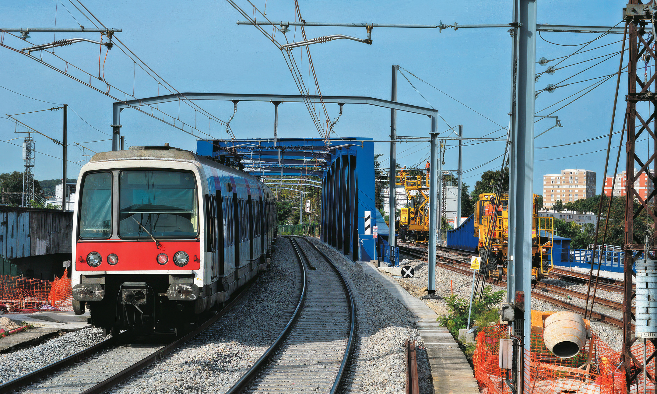 Un exemple de chantier nécessité par l’arrivée du nouveau matériel MI 20 : le remplacement du pont de Chartres, vu ici à Massy le 23 août 2023 avec une rame MI 79 en direction de Massy-Palaiseau ; à droite, les travaux de finitions sur l’ouvrage SNCF du RER C dit pont de Gallardon.