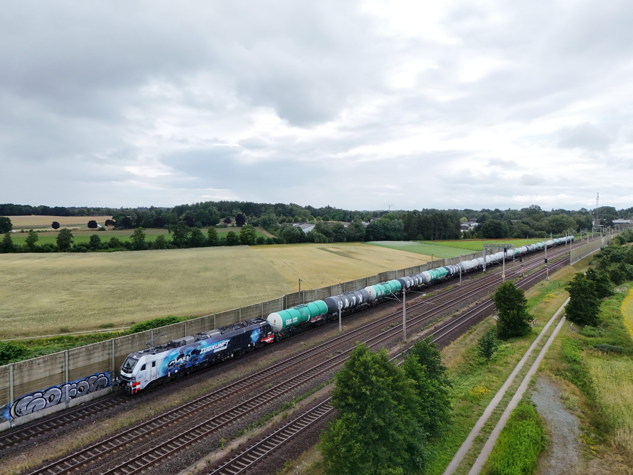 Suisse : ELP commande auprès de Stadler 20 EuroDual supplémentaires 2 DJI 507: Un train de wagons-citernes transportant du biofuel pour le compte de M.A.D. LogistIk remorqué par l’EuroDual 159 208-8 appartenant à ELPet louée à l’opérateur fret BSAS EisenbahnVerkehrs GmbH est aperçu peu avant la gare d’Ashausen (8 juillet 2025) Crédit photo Luc LEVERT