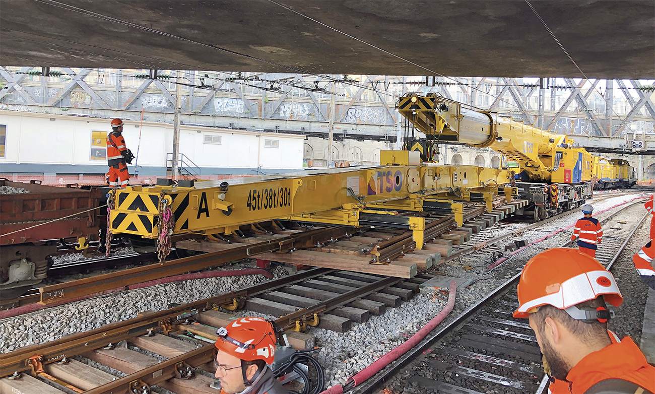 Remplacement d’appareils de voie : trois chantiers, trois méthodes 1 Sur le chantier de Paris-Est, la grue Kirow transporte l’appareil neuf à son emplacement (24 mai 2025).