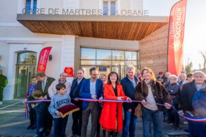 Légende : Carole Delga (en rouge) coupe le ruban de l’inauguration de la gare de Martres-Tolosane le 13 décembre 2025 (© Région Occitanie).